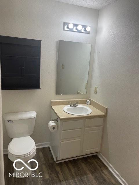 8249 Retreat Ln, Indianapolis, IN 46259 - bathroom with vanity, toilet, baseboards, a textured ceiling, and wood finished floors