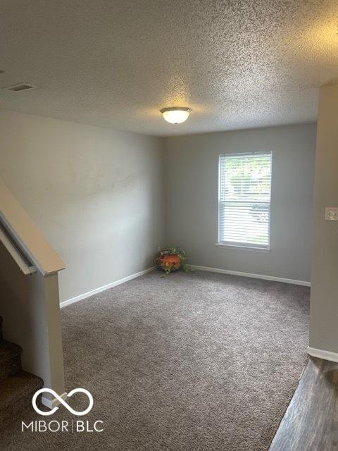 8249 Retreat Ln, Indianapolis, IN 46259 - carpeted empty room with baseboards, visible vents, stairway, and a textured ceiling