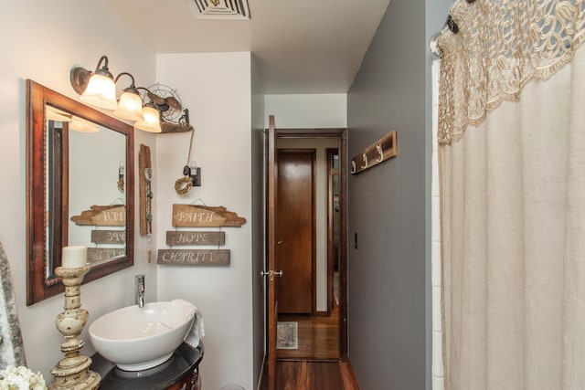 bathroom featuring curtained shower, visible vents, a sink, and wood finished floors