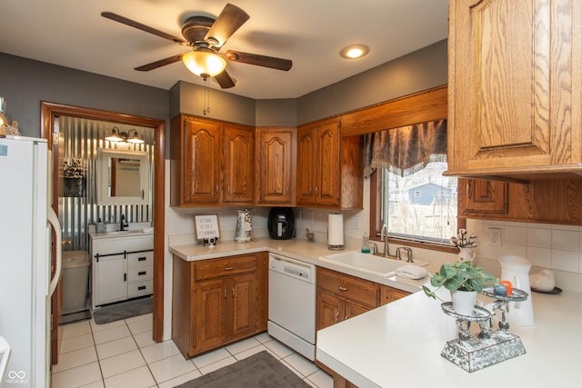 kitchen with white appliances, a sink, light countertops, backsplash, and brown cabinets