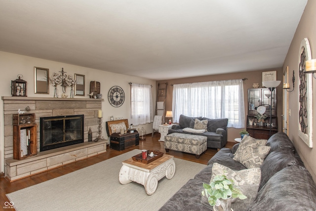 living room with a stone fireplace, plenty of natural light, and wood finished floors