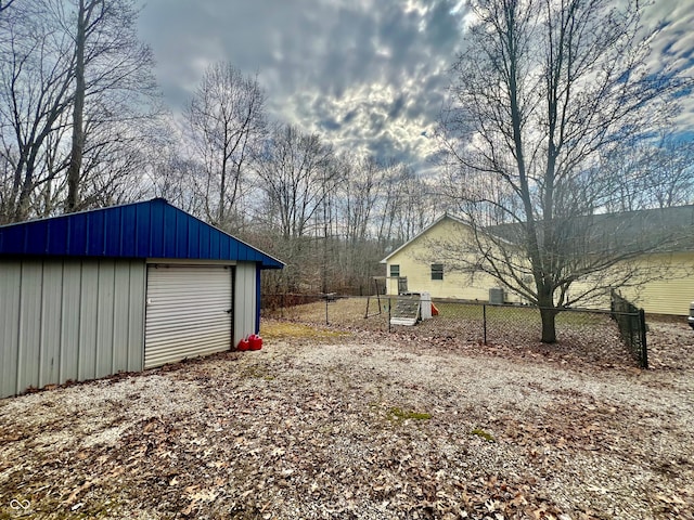 view of yard with dirt driveway, an outdoor structure, fence, and a garage