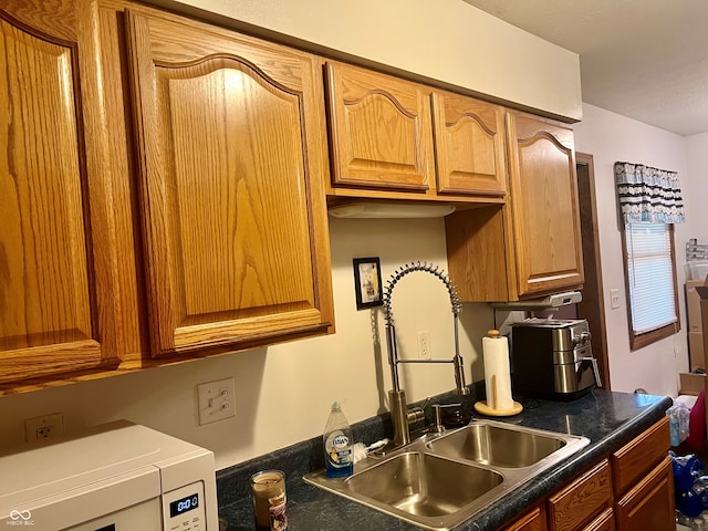 kitchen with dark countertops, brown cabinets, and a sink