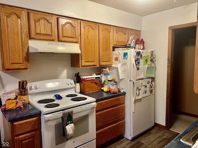 kitchen with white appliances, dark countertops, brown cabinets, dark wood-type flooring, and under cabinet range hood