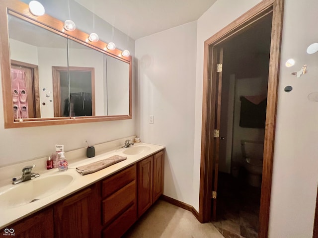 full bathroom with double vanity, baseboards, toilet, and a sink