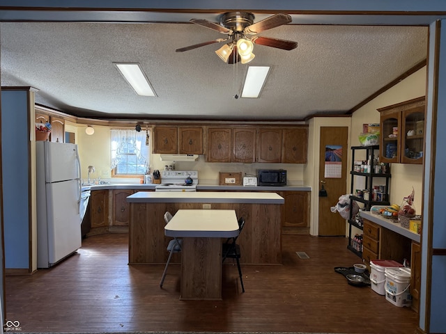 kitchen with white appliances, a kitchen island, light countertops, a kitchen bar, and glass insert cabinets