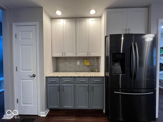 kitchen with white cabinets, dark wood-style floors, stainless steel fridge, and decorative backsplash