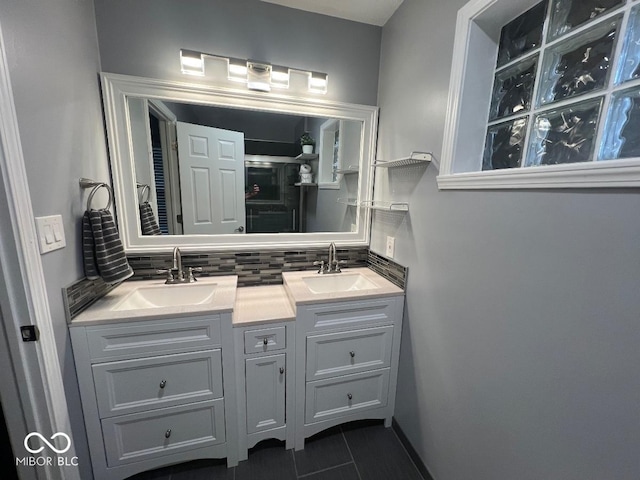 full bath featuring double vanity, decorative backsplash, a sink, and tile patterned floors