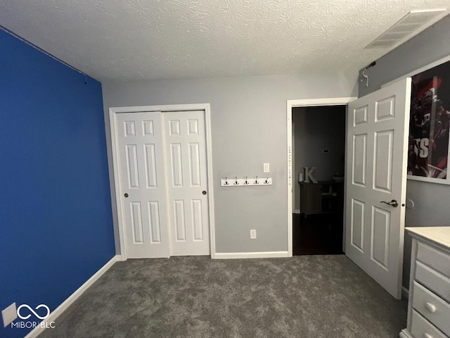 unfurnished bedroom featuring baseboards, visible vents, a textured ceiling, dark carpet, and a closet