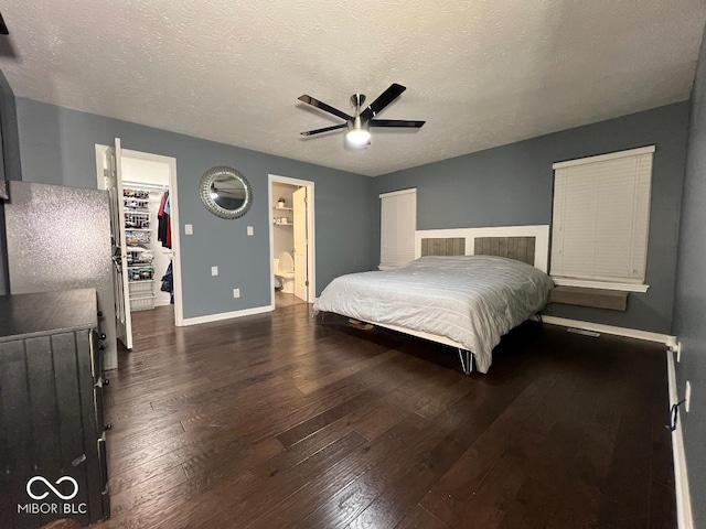 bedroom featuring a textured ceiling, a spacious closet, a closet, and dark wood finished floors