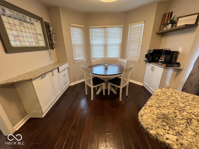 dining room with dark wood finished floors, a textured ceiling, and baseboards