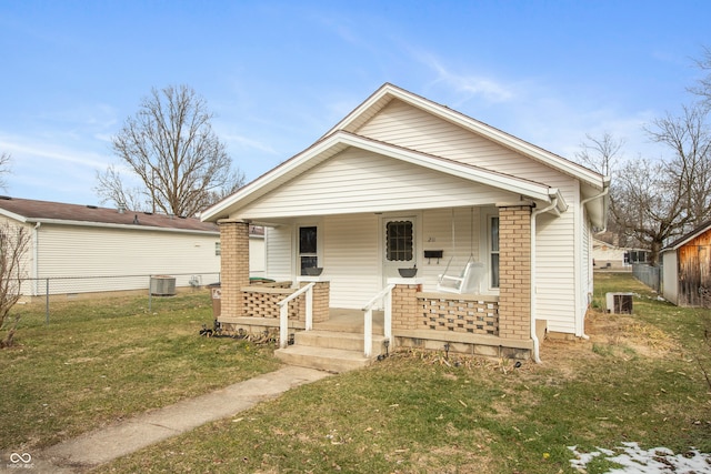 bungalow-style house featuring a porch, a front yard, brick siding, and fence