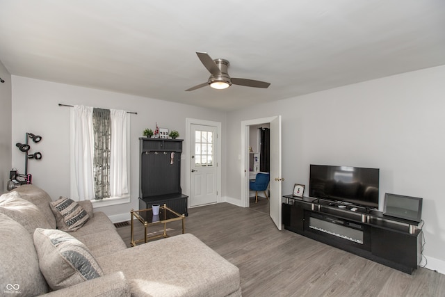 living room with a ceiling fan, baseboards, and wood finished floors