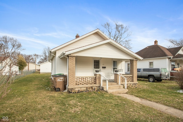 bungalow-style house with covered porch, a chimney, a front lawn, and brick siding