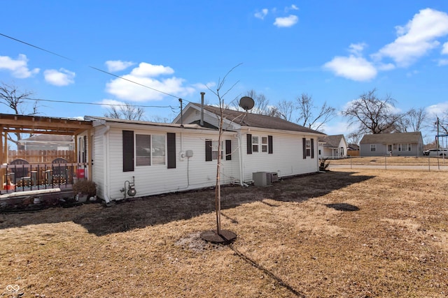 rear view of house featuring a lawn, fence, and central AC