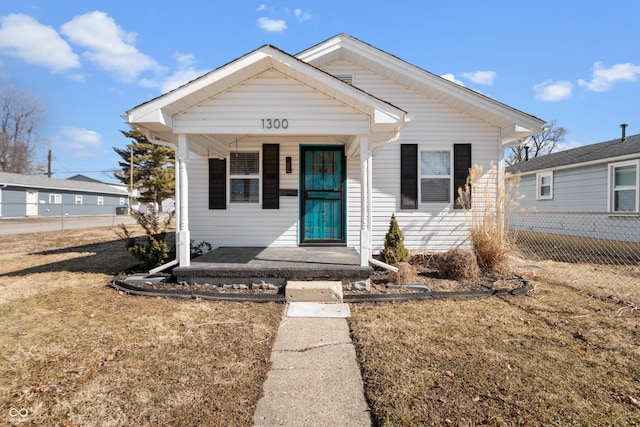 bungalow with a porch, a front yard, and fence