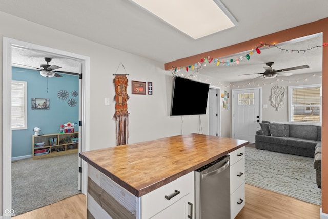 kitchen with light wood finished floors, stainless steel dishwasher, white cabinets, ceiling fan, and wood counters