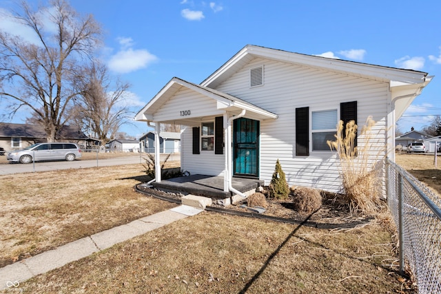 bungalow featuring a front lawn, fence, a porch, and a carport