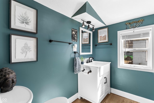 half bathroom featuring vanity, wood finished floors, toilet, and baseboards