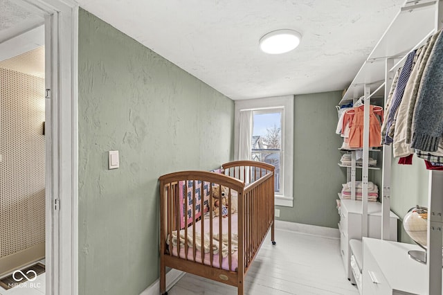 bedroom with baseboards, wood finished floors, and a textured wall