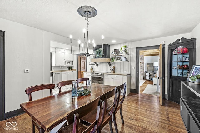 dining space with baseboards, an inviting chandelier, and wood finished floors