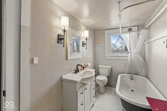 bathroom with toilet, a soaking tub, a shower with curtain, and vanity