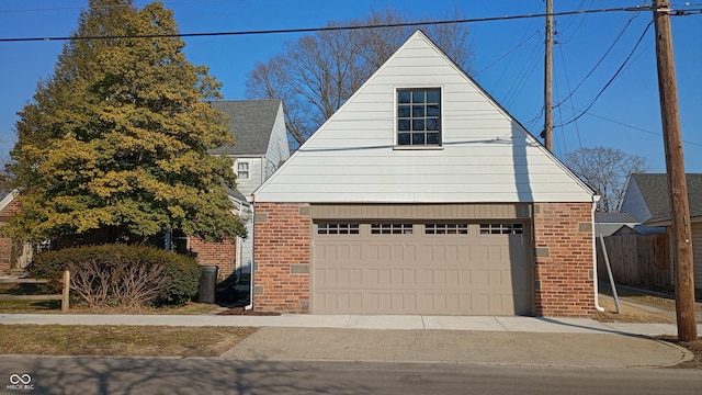 view of front of house featuring a garage, an outbuilding, brick siding, and fence