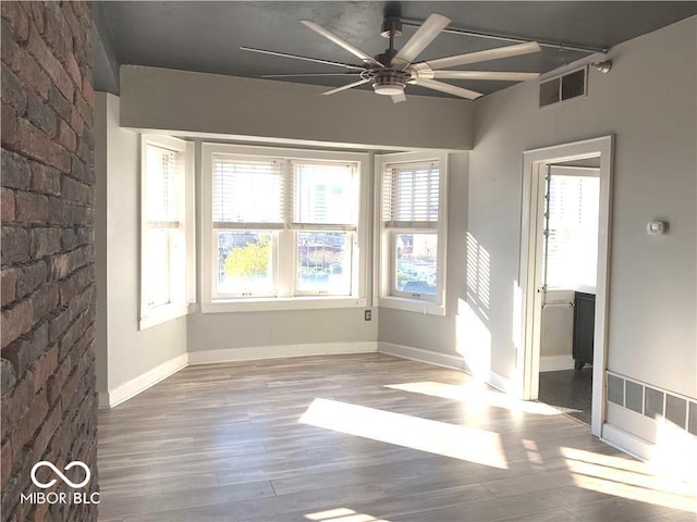 unfurnished room with baseboards, wood finished floors, visible vents, and a ceiling fan