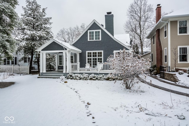 snow covered property featuring fence and a chimney