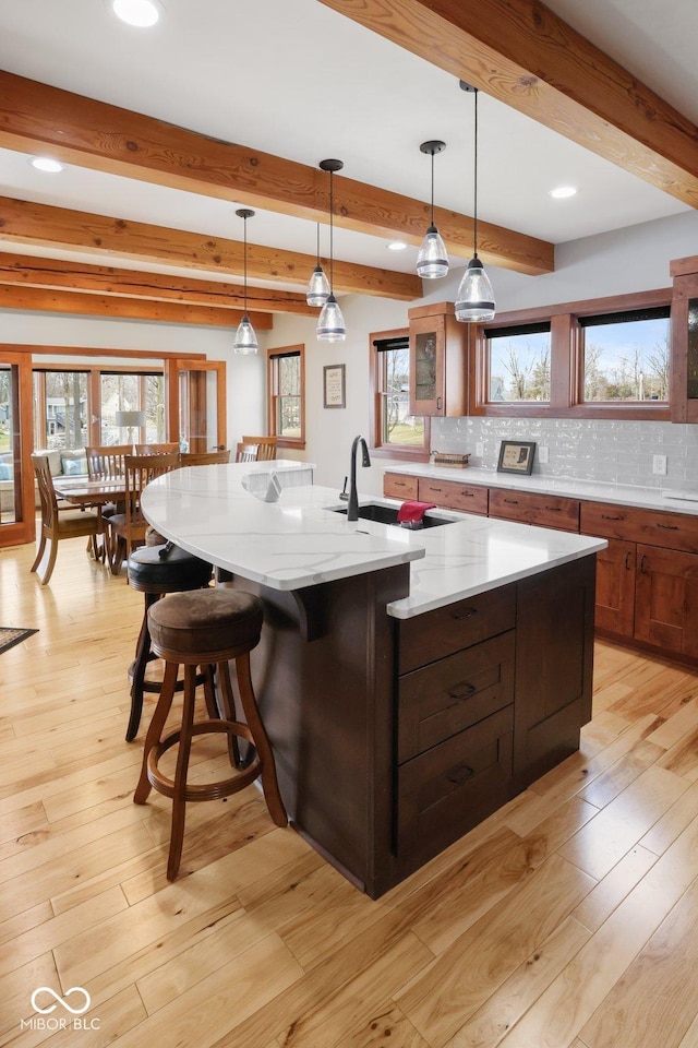 kitchen featuring light wood-style floors, backsplash, and a sink