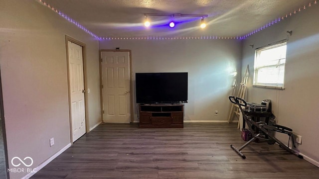 living area featuring rail lighting, a textured ceiling, baseboards, and wood finished floors