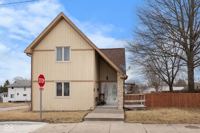 chalet / cabin with a shingled roof and fence