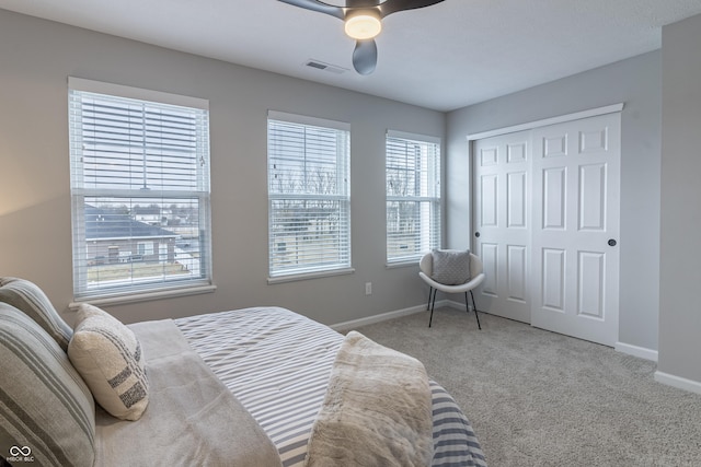 carpeted bedroom featuring a ceiling fan, baseboards, visible vents, and a closet