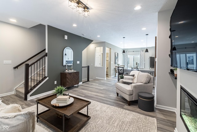 living area featuring light wood-style flooring, stairway, baseboards, and recessed lighting