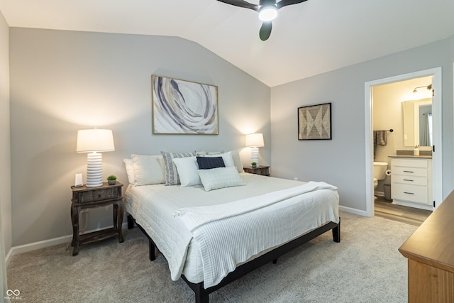 bedroom featuring light carpet, baseboards, vaulted ceiling, and ensuite bathroom