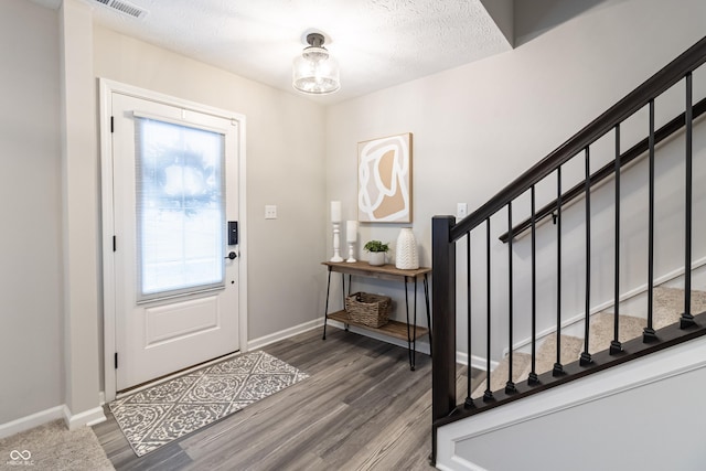 foyer with a healthy amount of sunlight, stairs, baseboards, and wood finished floors