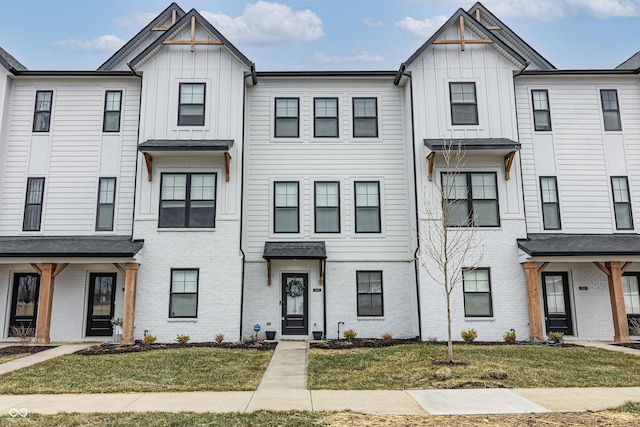 multi unit property featuring brick siding, board and batten siding, and a front yard