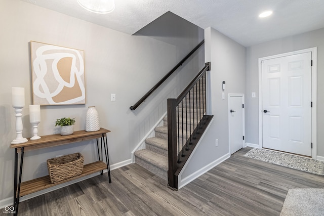 foyer with stairway, baseboards, and wood finished floors