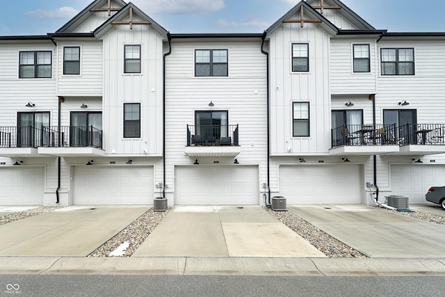 view of front facade with central AC, board and batten siding, and concrete driveway