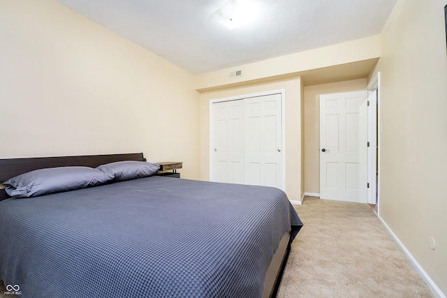 bedroom with visible vents, baseboards, a closet, and light colored carpet