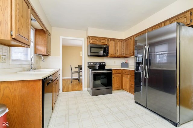 kitchen with appliances with stainless steel finishes, brown cabinets, a sink, and decorative backsplash