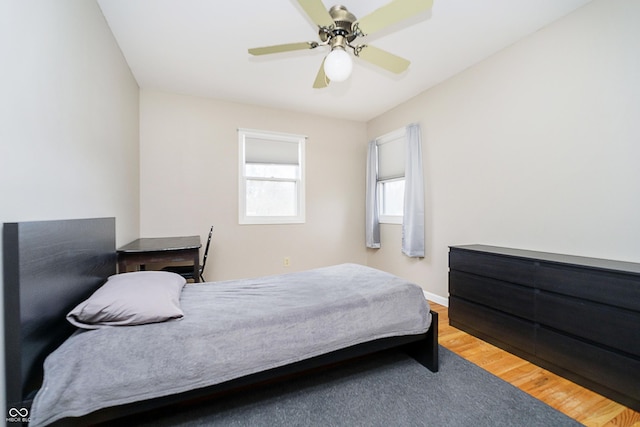 bedroom featuring wood finished floors, a ceiling fan, and baseboards