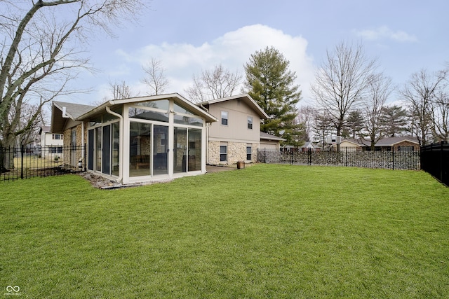 rear view of property featuring a sunroom, a fenced backyard, stone siding, and a yard