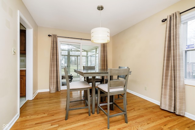 dining space with a wealth of natural light, baseboards, and light wood finished floors