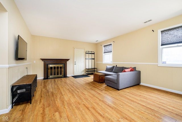 living area with light wood finished floors, a fireplace with flush hearth, and visible vents