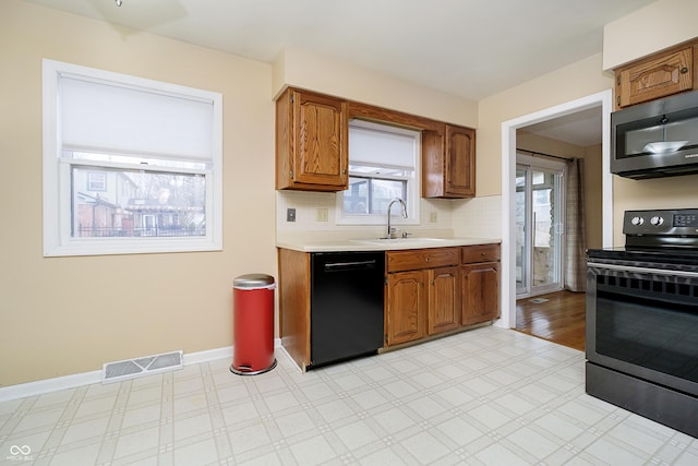 kitchen with range with electric cooktop, visible vents, black dishwasher, light countertops, and light floors