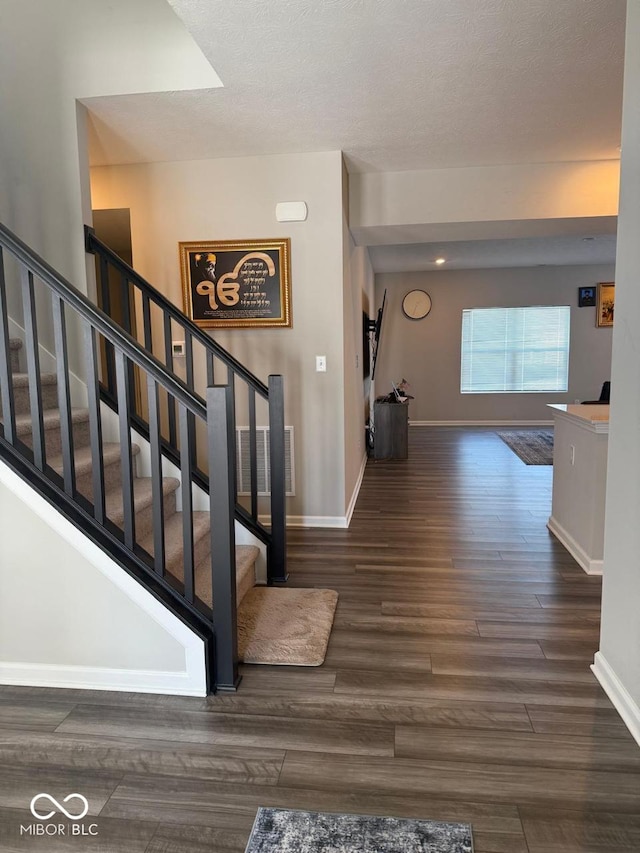 staircase with visible vents, baseboards, and wood finished floors