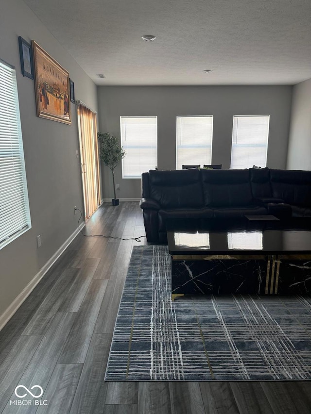 living room with baseboards, a textured ceiling, and dark wood-style floors