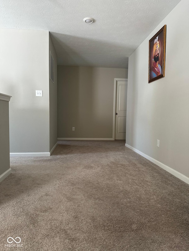 empty room with visible vents, carpet, baseboards, and a textured ceiling