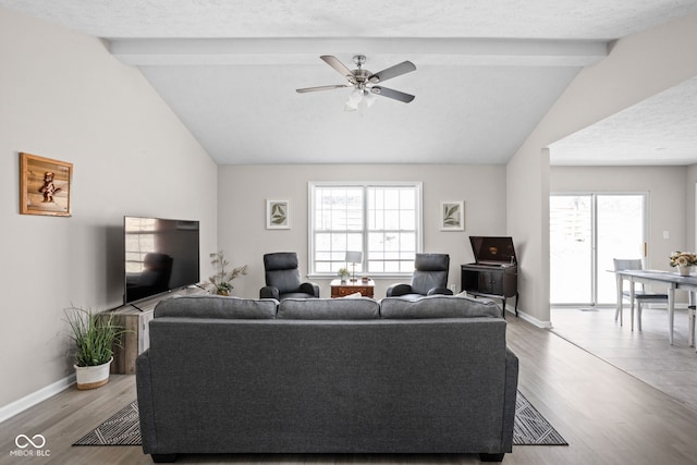 living room with vaulted ceiling with beams, baseboards, and a textured ceiling